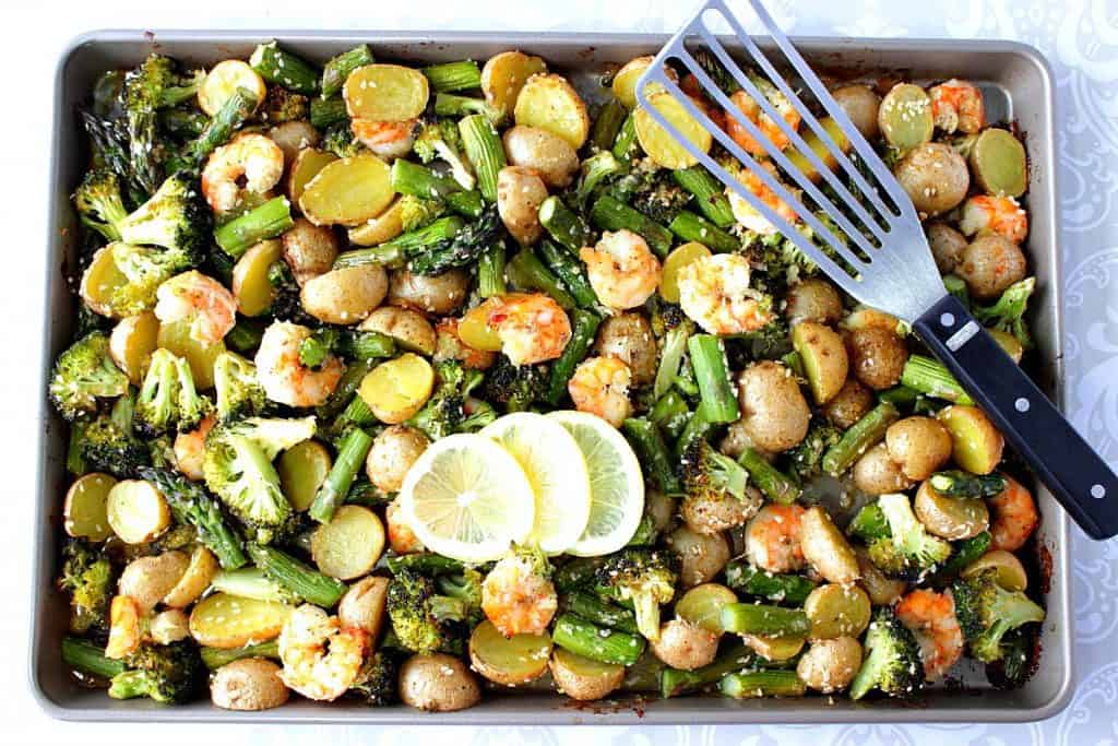 Overhead photo of a sheet pan with shrimp, potatoes, broccoli and asparagus.