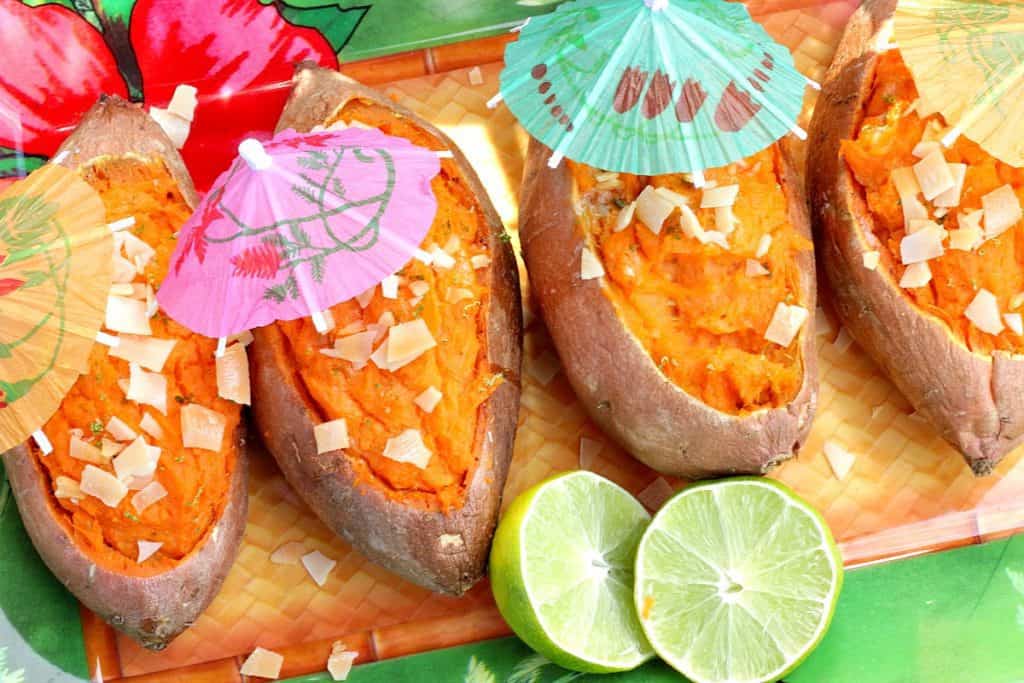 An overhead photo of 4 tropical sweet potatoes with colorful umbrellas and lime slices.