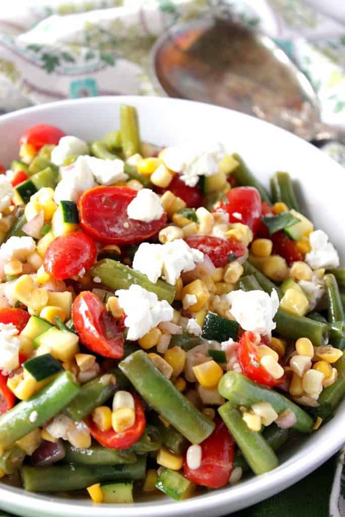 Vertical closeup photo of a Farmer's Market Vegetable Salad with green beans, tomatoes, corn, and goat cheese. Healthy Salad Recipe Roundup.