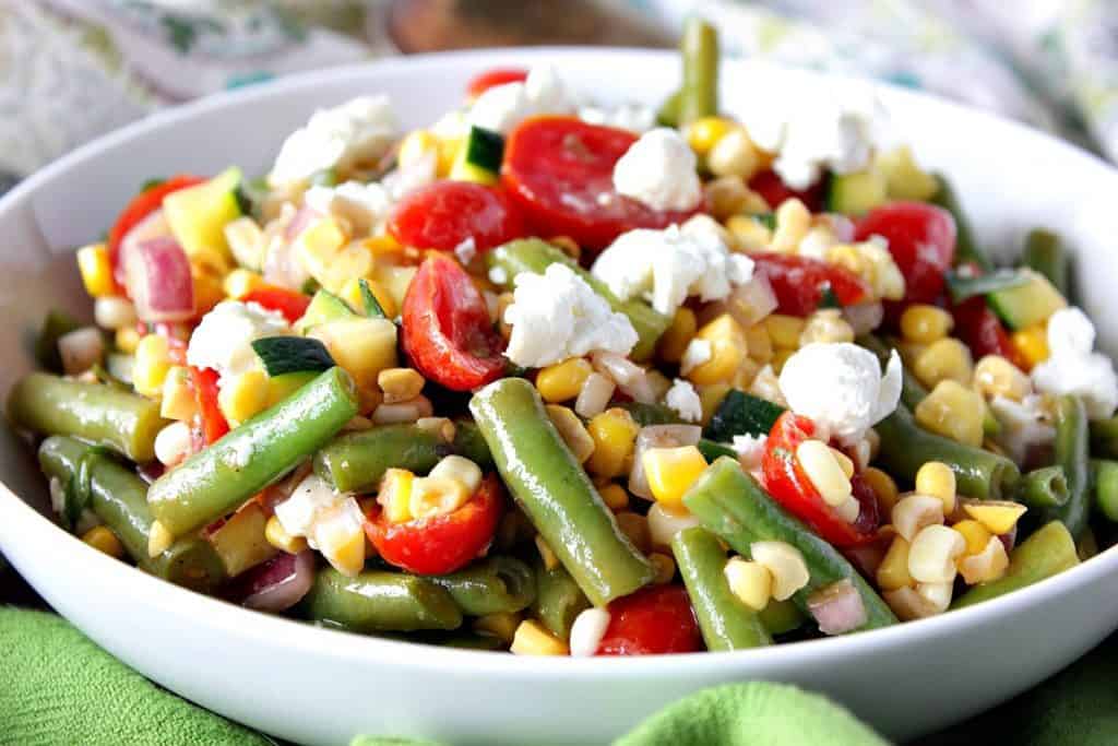 Colorful farmer's Market Veggie Salad in a white bowl with a green napkin.