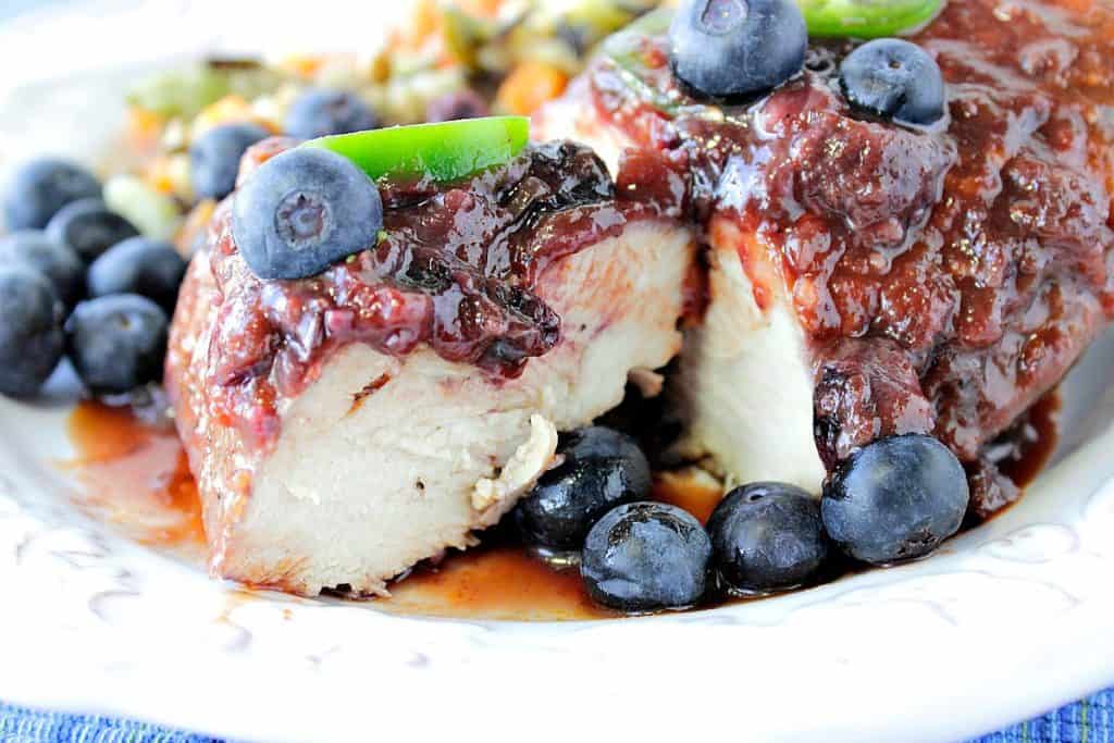 Cooked and cut chicken breast with blueberry BBQ sauce, fresh blueberries, and sliced jalapeno peppers.