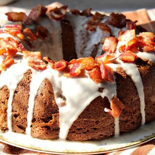 A glazed Bacon Root Beer Bundt Cake on a plate in the sunshine.