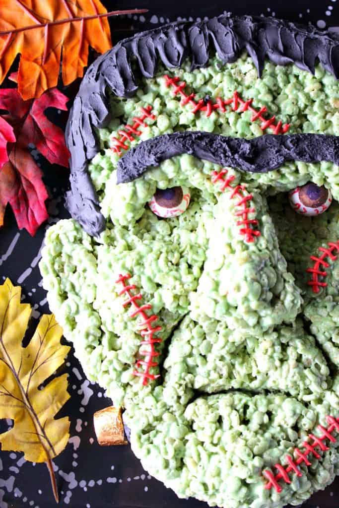 If you're intimidated or scared by the looks of this Frankenstein rice cereal Halloween treat because you think you wouldn't have success making him yourself, I'm here to prove you wrong! - Kudos Kitchen by Renee Overhead closeup photo of Frankenstein Rice Krispie Treat with Gumball Eyes