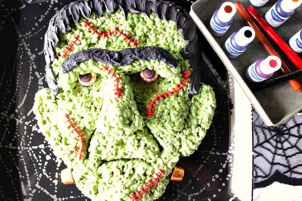 If you're intimidated or scared by the looks of this Frankenstein rice cereal Halloween treat because you think you wouldn't have success making him yourself, I'm here to prove you wrong! - Kudos Kitchen by Renee Frankenstein Rice Krispie Treat featuring AmeriColor food color in the corner.