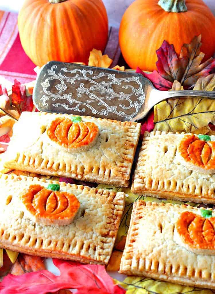 Vertical image of cute pumpkin hand pies on a platter with a serving spatula for Thanksgiving dessert recipe roundup