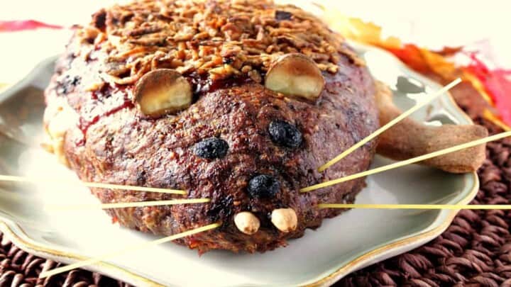 A horizontal photo of a Rat Loaf Meatloaf on a platter with almond teeth, spaghetti whiskers, olive eyes, and potato ears.