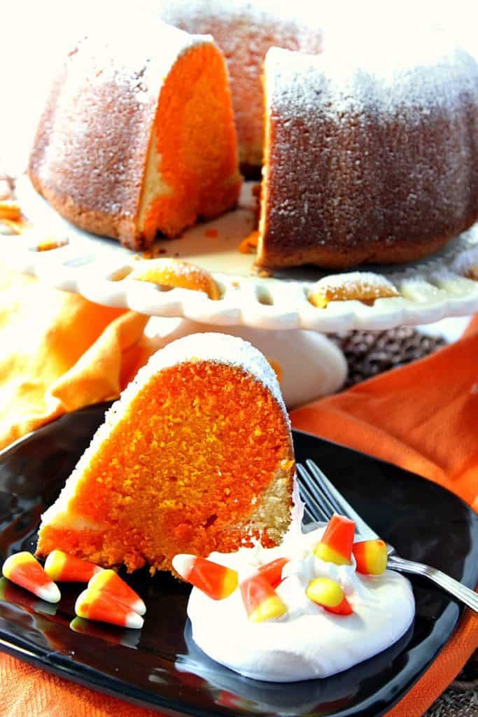 Vertical image of a slice of candy corn citrus flavored pound cake on a black plate with whipped cream and candy corn.