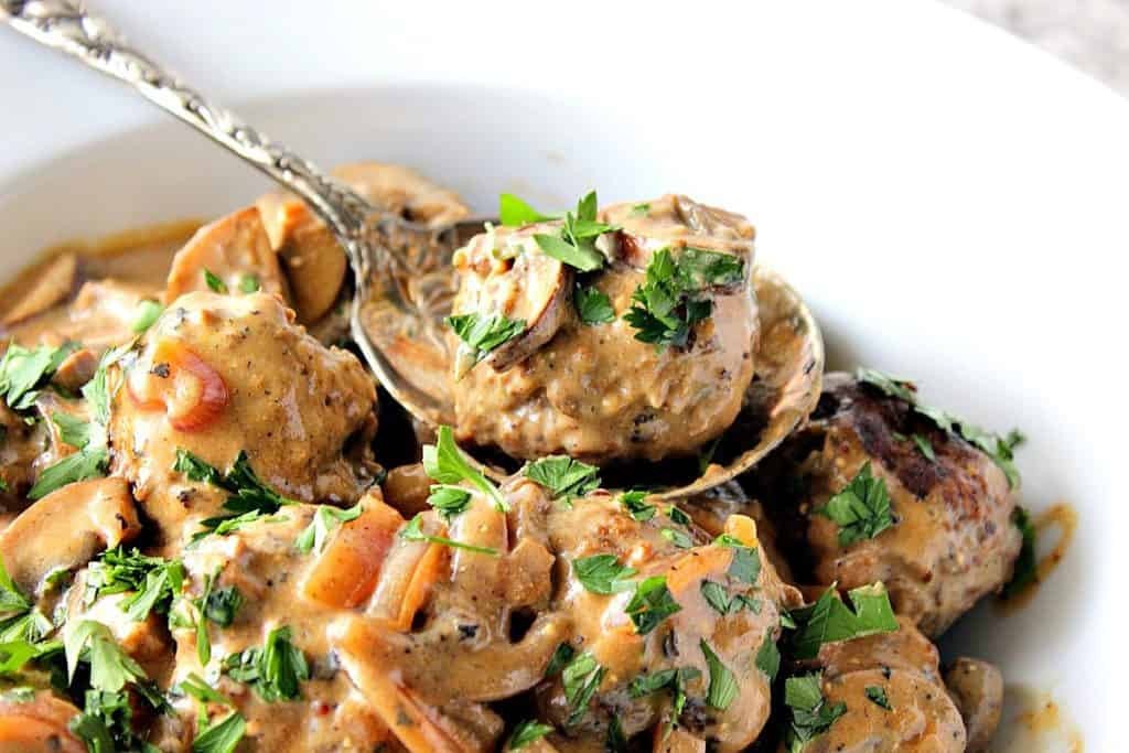 German meatball with caraway mushroom cream sauce on a large spoon.