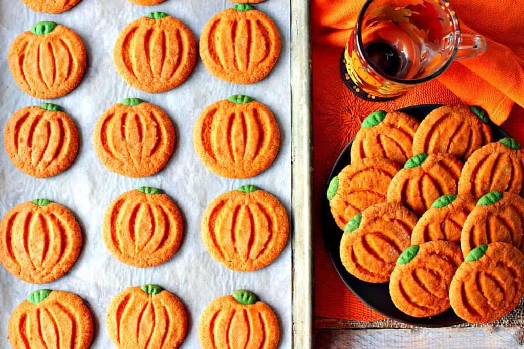 An overhead picture of a tray of pumpkin-shaped pumpkin cookies along with a plate filled with them.