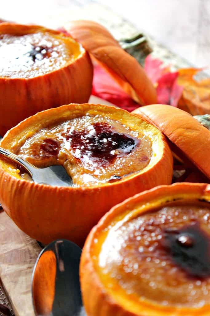 Closeup photo of a spoon digging into rustic pumpkin creme brulee baked in real pumpkins.