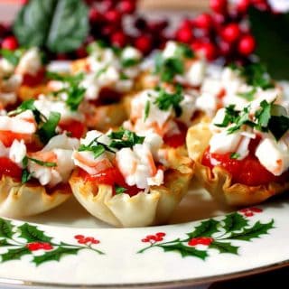 A plate filled with shrimp cocktail appetizer bites with cocktail sauce and parsley.