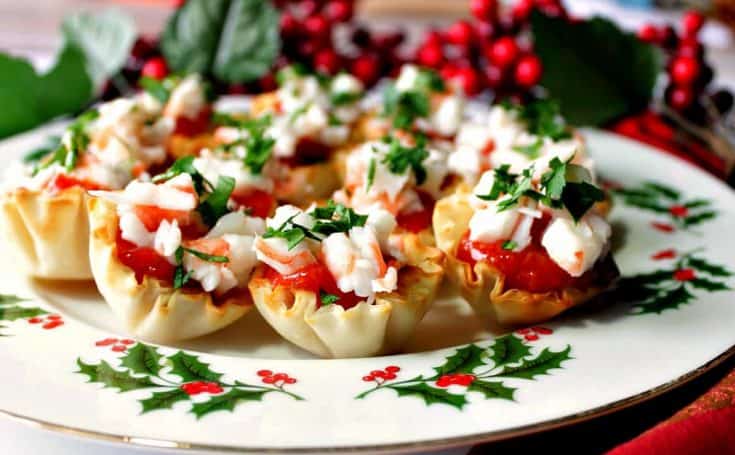 A plate filled with shrimp cocktail appetizer bites with cocktail sauce and parsley.