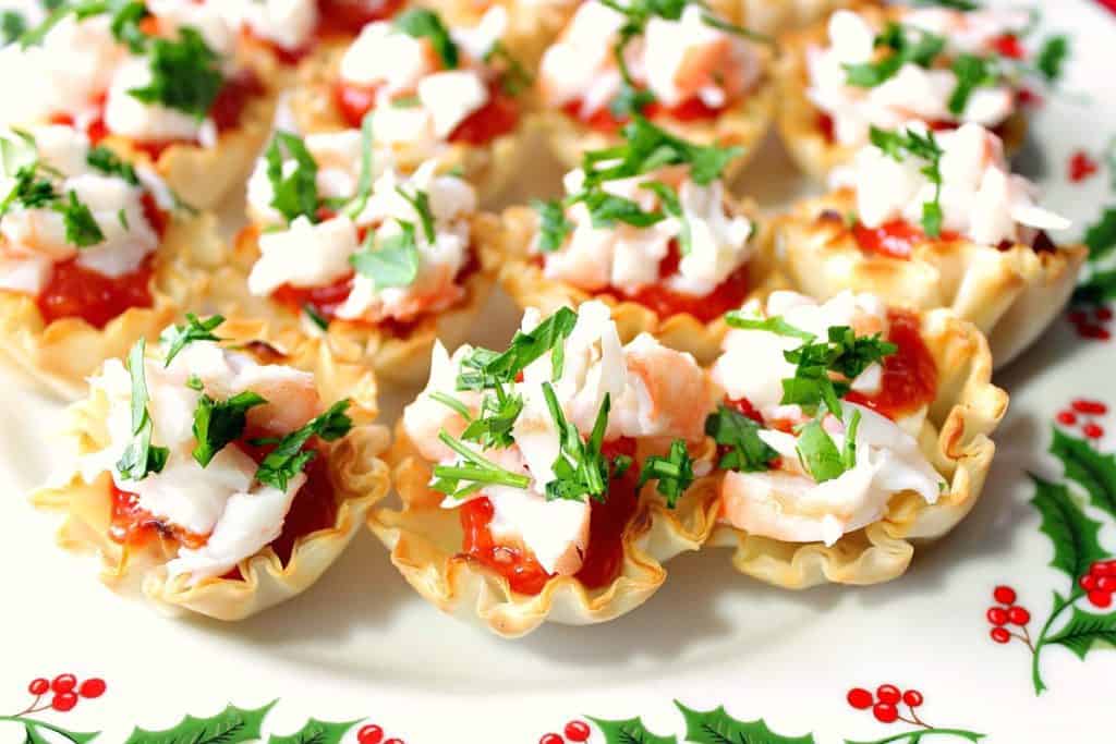 Festive Shrimp Cocktail Appetizer Bites with Homemade Cocktail Sauce on a holly berry platter with fresh parsley