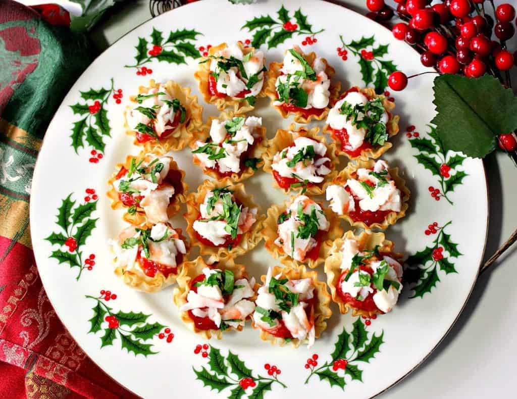 Overhead photo of a holiday plate with red and green accents filled with shrimp cocktail appetizer bites.