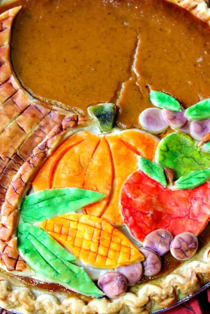 Closeup vertical image of a painted cornucopia pie crust on a pumpkin pie.