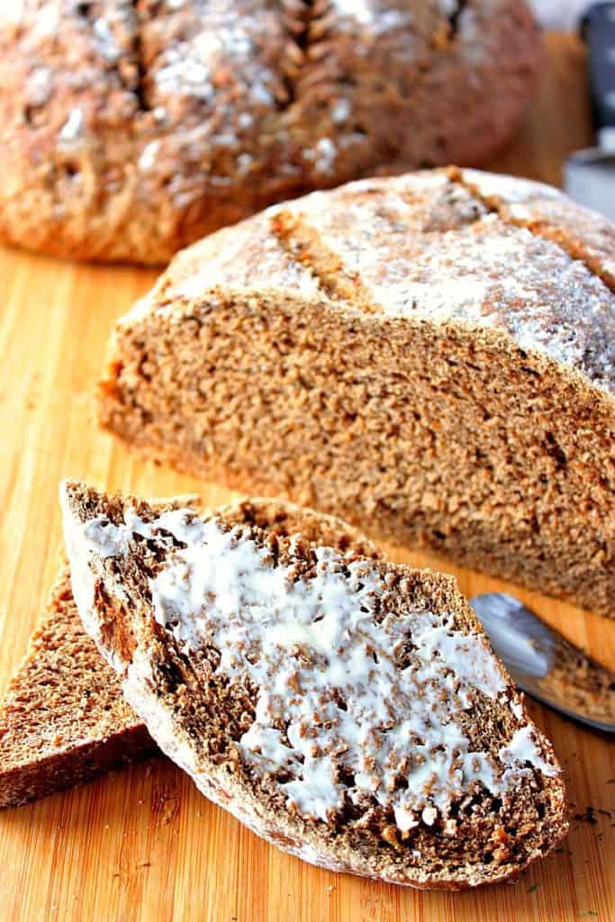 Two loaves of Onion Rye Bread with Dill on a wooden board.