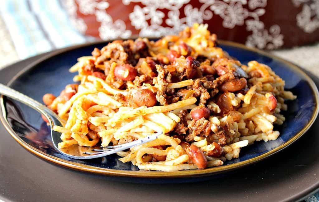 A horizontal photo of spaghetti western chili on a blue plate with a fork.