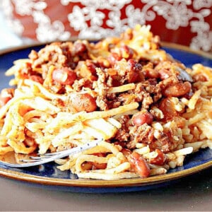 A serving of Spaghetti Western Chili on a blue plate with a fork.