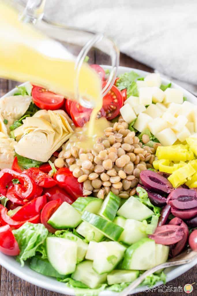 Closeup of dressing being poured over a colorful healthy salad.