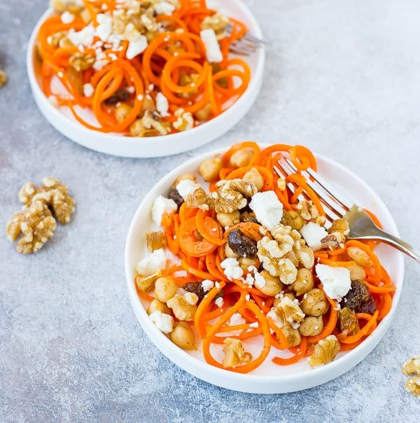 Carrot, walnut, and raisin salad in two white bowls with a fork for healthy salad recipe roundup.