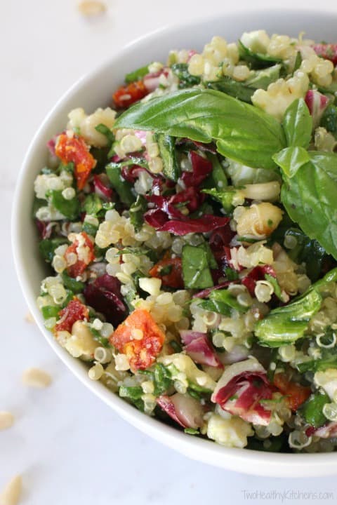 Closeup of quinoa, basil and lettuces in a bowl for healthy salad recipe roundup.