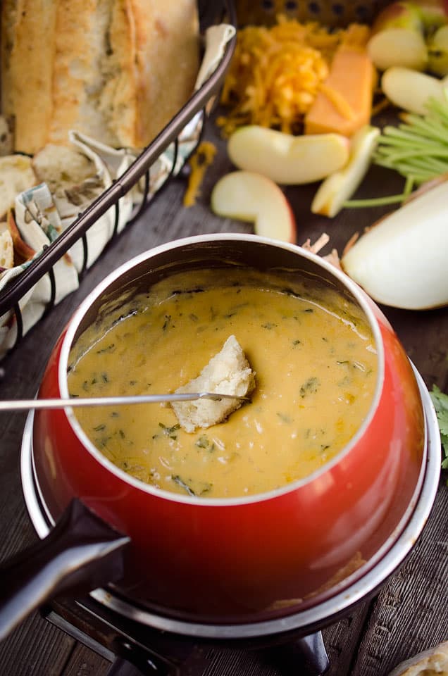 Cheese fondue with a dipper. New Years eve appetizers and drinks recipe roundup.