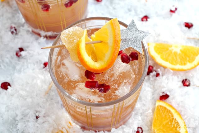 Overhead photo of a cocktail with and orange slice and a star. New Year's eve appetizers and drinks recipe roundup.