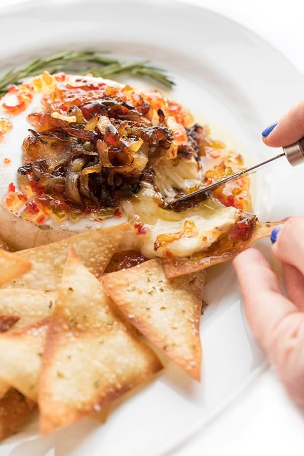 Closeup photo of cheese brie cheese with caramelized onions. New Years eve appetizers and drinks recipe roundup.