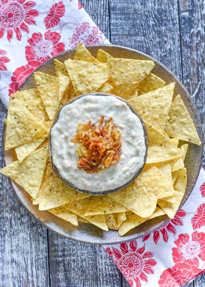 Overhead photo of tortilla chips on a round plate with dip. New Years eve appetizers and drinks recipe roundup.
