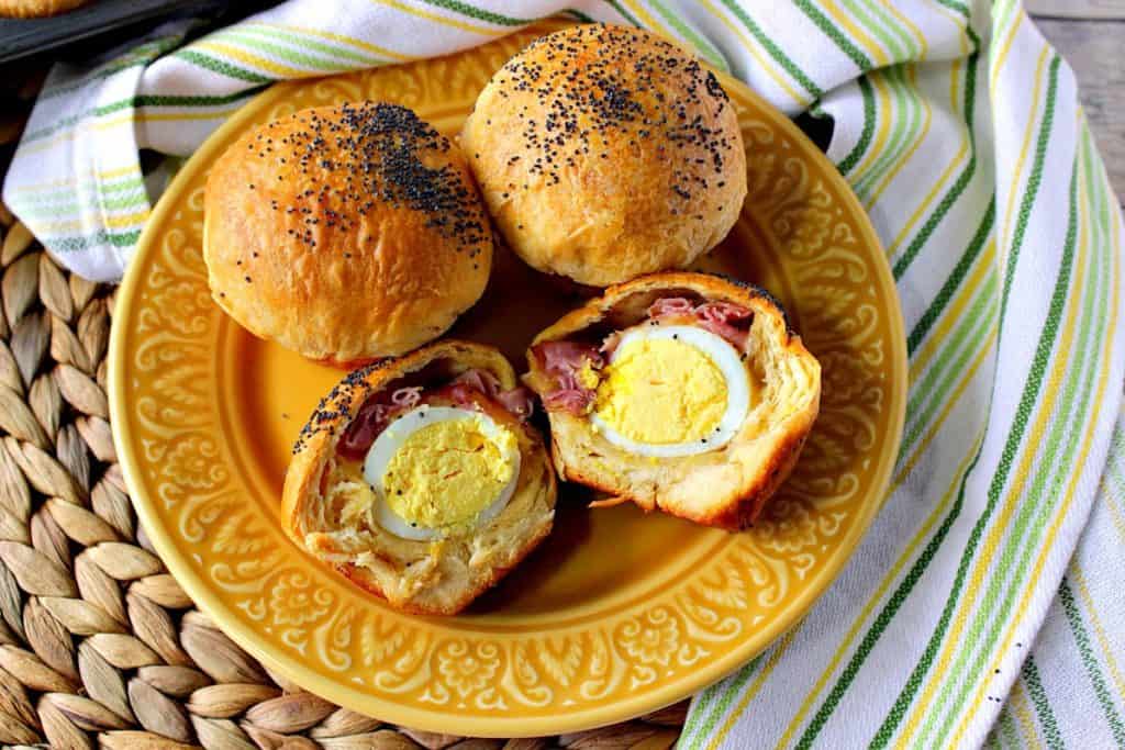 An overhead photo of easy breakfast recipe of egg stuffed biscuits with a green, yellow and white striped napkin in the background.