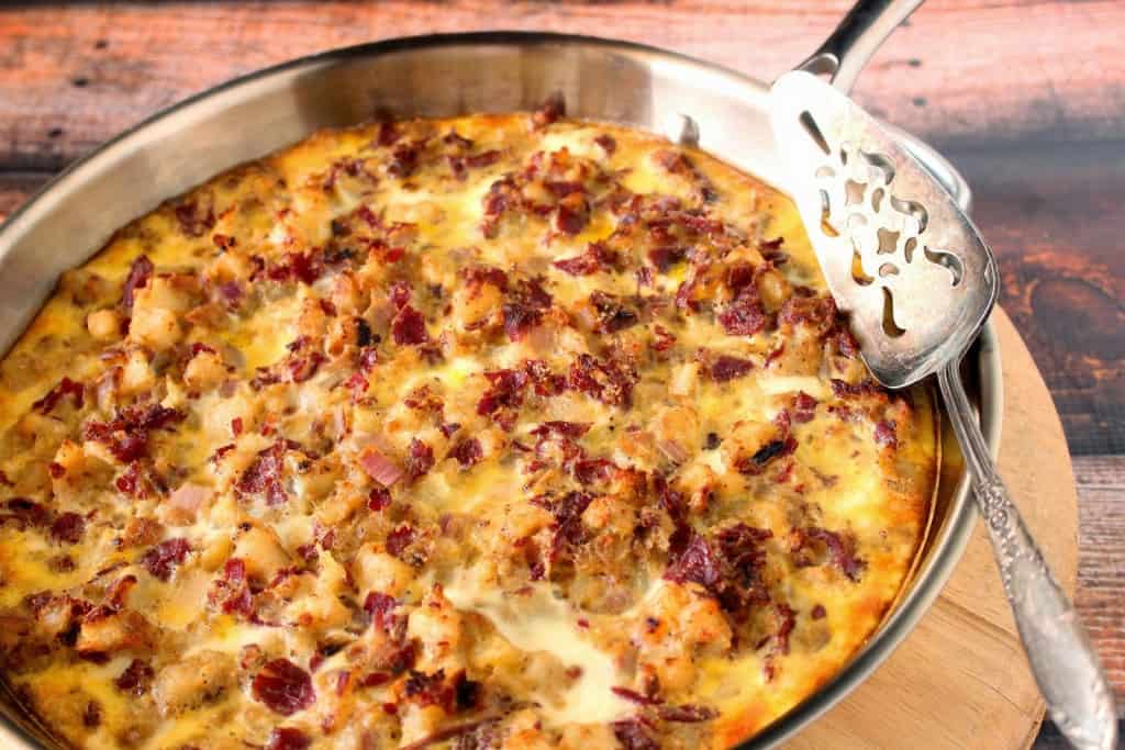 Corned beef hash frittata in a silver skillet with a silver spatula.