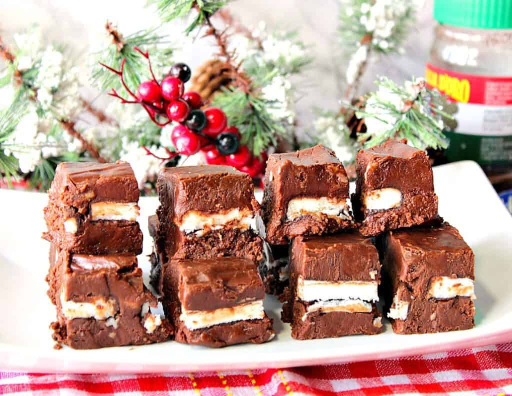 A stack of fudge on a white plate with espresso powder in the background.