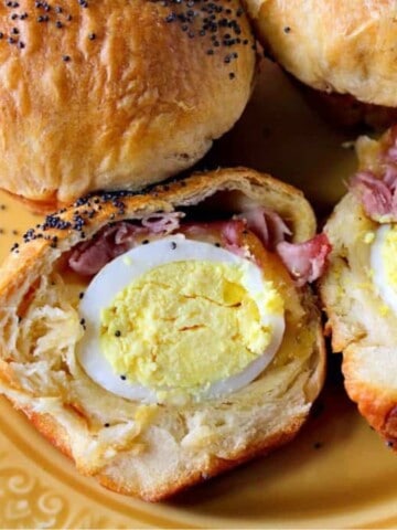 A hard boiled egg inside a biscuit with ham and cheese.