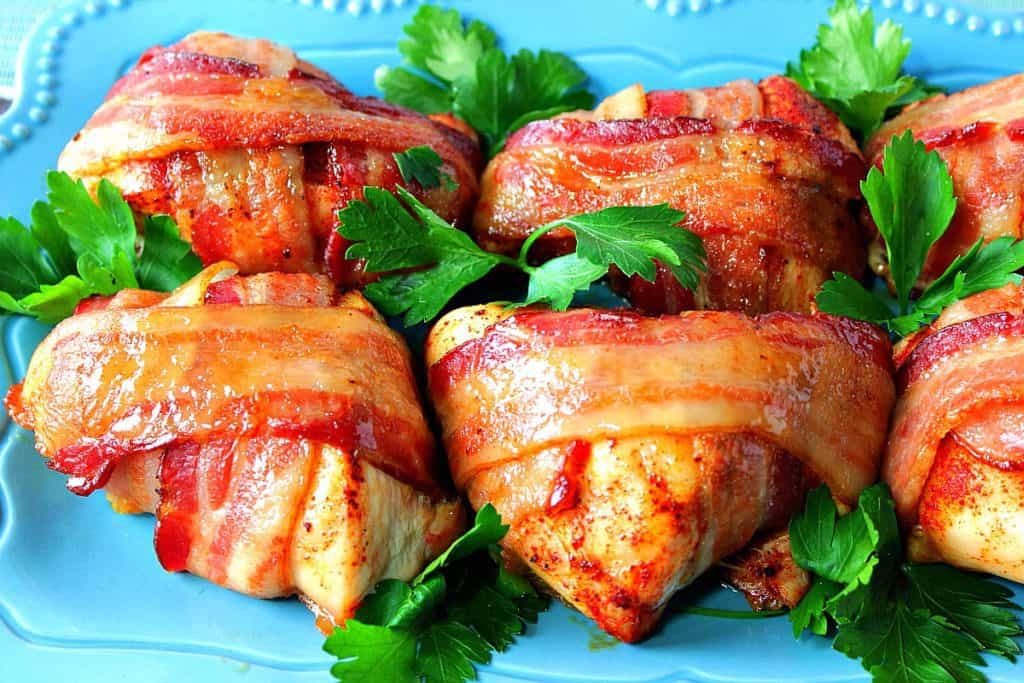 Smoky Sweet Bacon Wrapped Chicken Breasts on a blue plate with parsley as garnish.