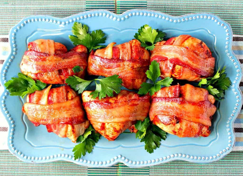 An overhead photo of a blue plate filled with Smoky Sweet Bacon Wrapped Chicken Breast and green parsley