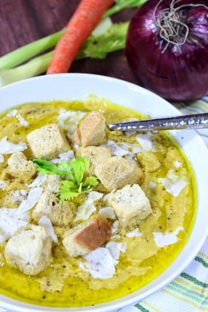 A vertical photo of a white bowl of cream of celery soup with a carrot, celery, and a red onion in the background and croutons on the top. Soup, Stew & Chowder Recipe Roundup