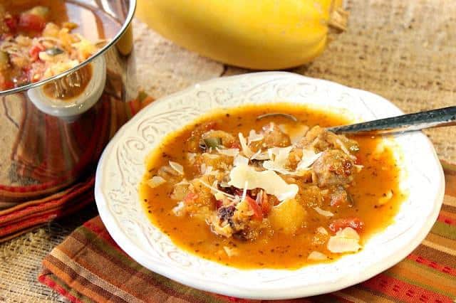 A horizontal photo of a bowl of spaghetti squash soup with Parmesan cheese garnish and a spoon. Soup, Stew & Chowder Recipe Roundup 