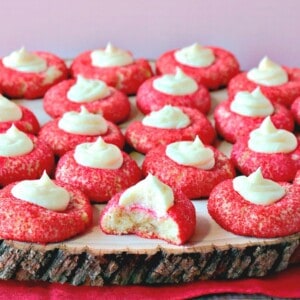 Red Cream Cheese Cookies with a Cheesecake Dollop on a wooden platter.