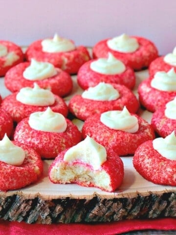 Red Cream Cheese Cookies with a Cheesecake Dollop on a wooden platter.