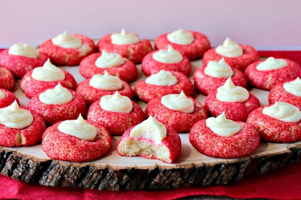 A bunch of cream cheese cookies on a wooden serving tray.