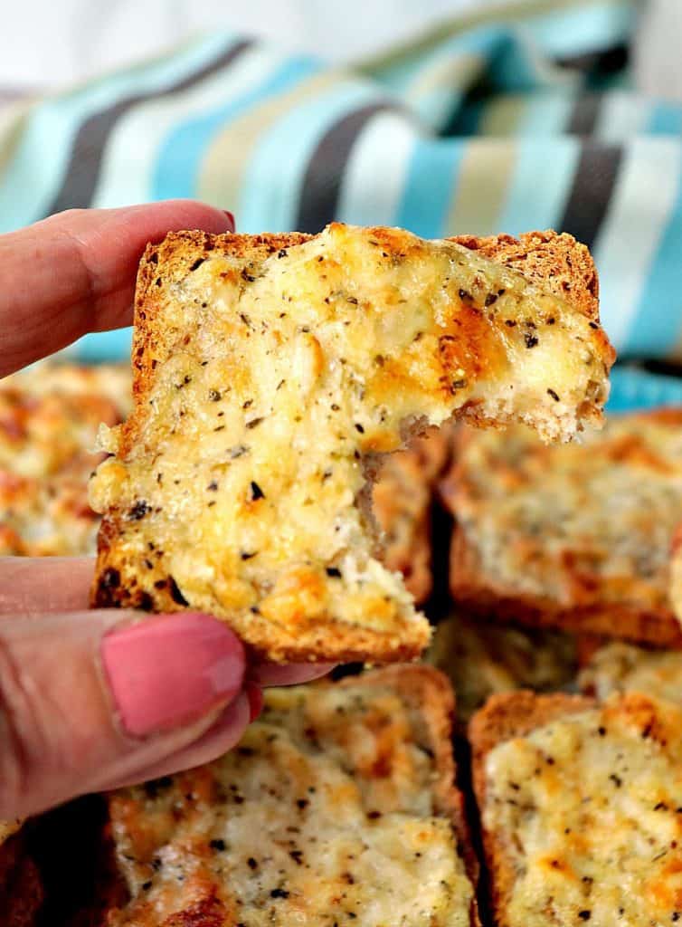 Vertical closeup image of a Parmesan Onion Appetizer Square with a bite taken.