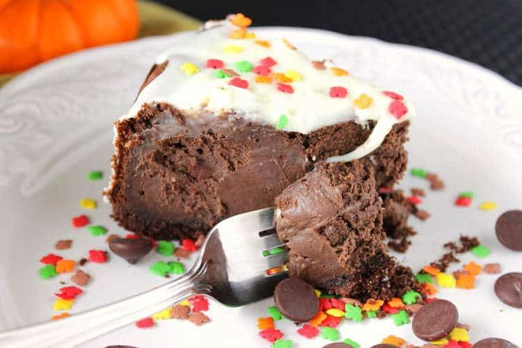 A horizontal photo of a slice of double chocolate cheesecake with chocolate cracker crust with a fork on a white plate. Romantic Valentine's Day chocolate dessert recipes roundup.