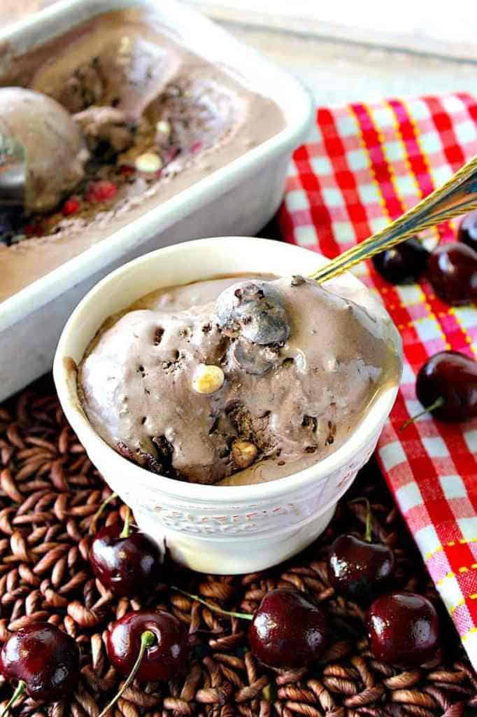 A vertical photo of a melting dish of chocolate cherry Kahlua ice cream with cherries and a spoon. Best Chocolate dessert recipes.