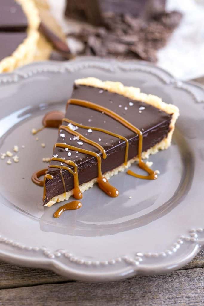 A slice of a chocolate tart on a plate for Valentine's Day chocolate dessert recipes collection