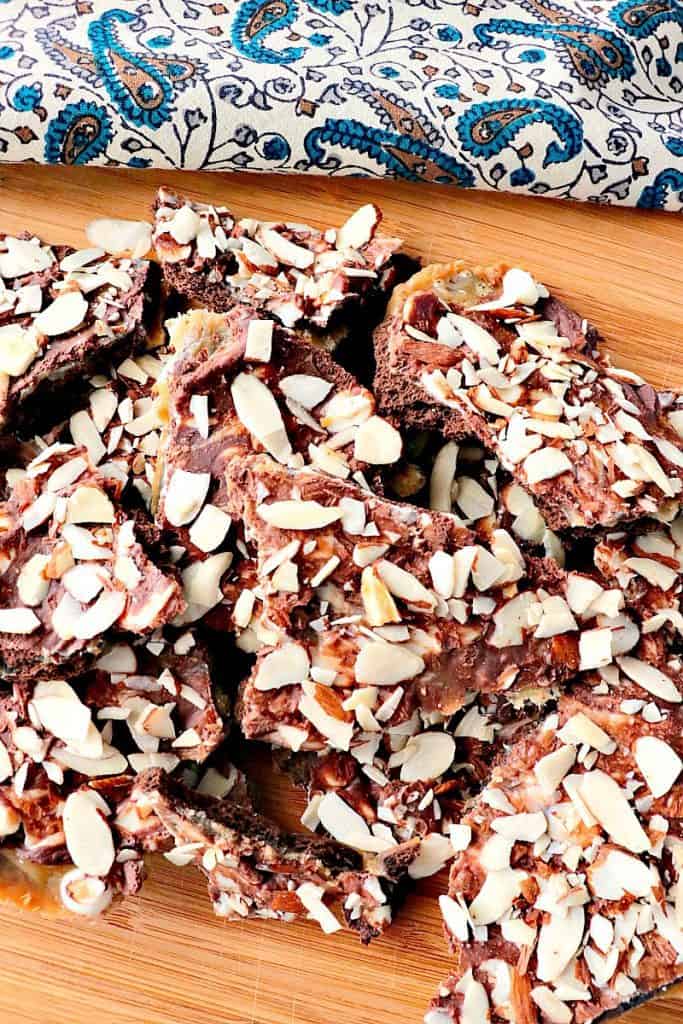 Vertical photo of a pile of double chocolate graham cracker toffee with a blue and brown napkin in ht e background.