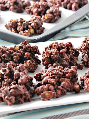 A white platter filled with Chocolate and Peanut Butter Granola Jumbles and a baking sheet with the jumbles in the background.