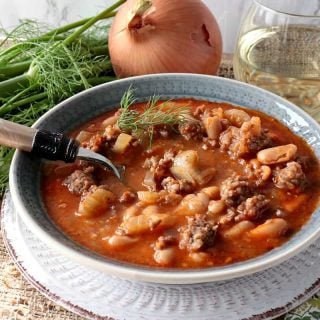 A hearty bowl of White Bean, Fennel & Italian Sausage Soup with Fennel, Onion and a glass of wine.