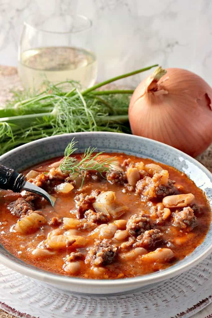 A hearty bowl of White Bean, Fennel & Italian Sausage Soup with Fennel, Onion and a glass of wine. 