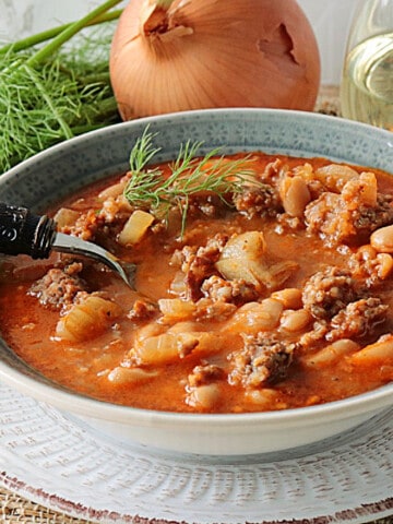 A delicious looking bowl of Italian Sausage, Fennel and White Bean Soup in a bowl with a spoon.