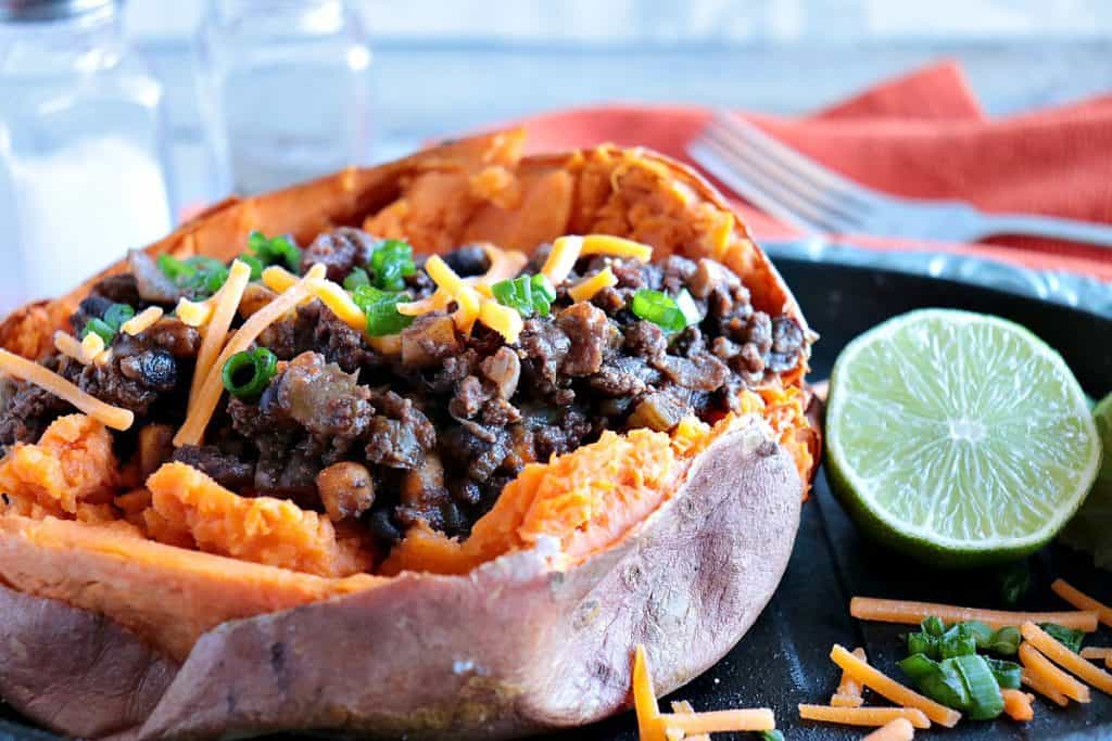 Tex-Mes Stuffed Sweet Potatoes with ground beef, cheddar cheese, and scallions with a lime.